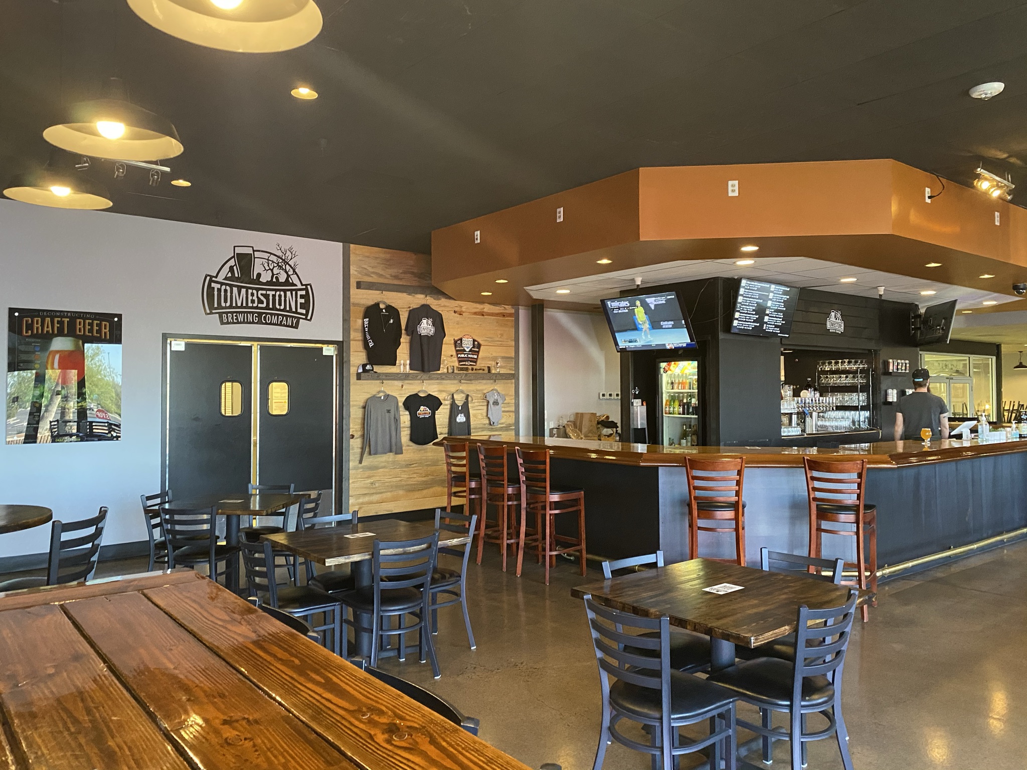 inside tombstone brewing phoenix showing the bar, apparel, and tables